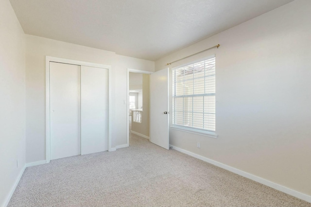 unfurnished bedroom with a closet, carpet flooring, and baseboards