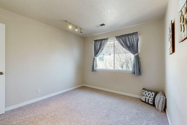 carpeted empty room featuring baseboards, visible vents, and a textured ceiling