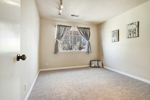 carpeted empty room featuring visible vents, a textured ceiling, and baseboards