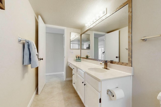 bathroom featuring a textured ceiling, vanity, and baseboards