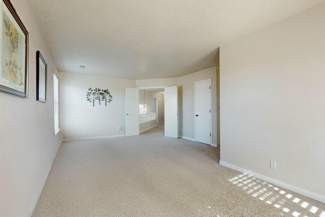 spare room featuring a textured ceiling, visible vents, and baseboards