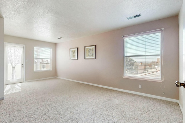 unfurnished room with carpet floors, visible vents, a textured ceiling, and baseboards