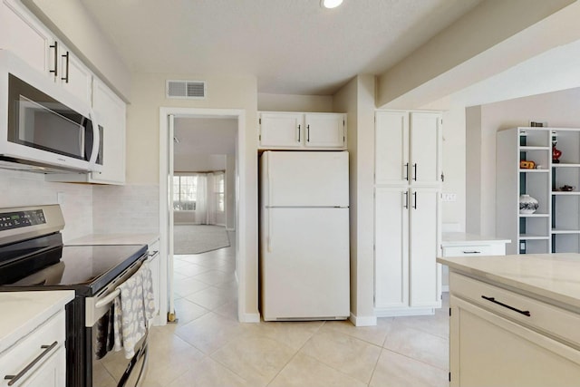 kitchen with visible vents, decorative backsplash, stainless steel electric range oven, freestanding refrigerator, and white cabinetry