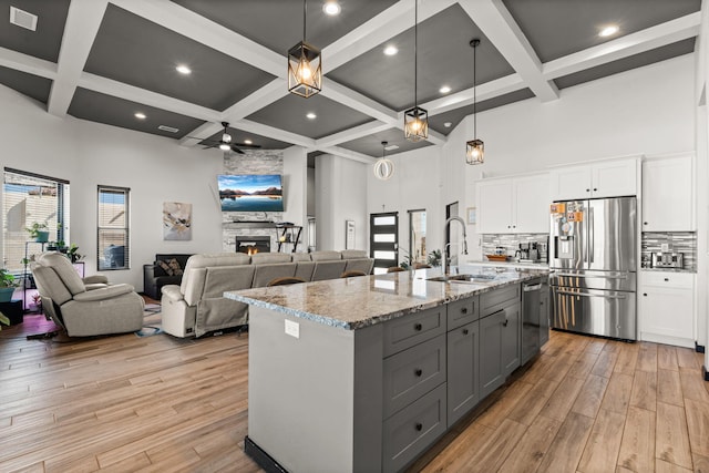 kitchen featuring stainless steel appliances, a fireplace, a sink, and a high ceiling