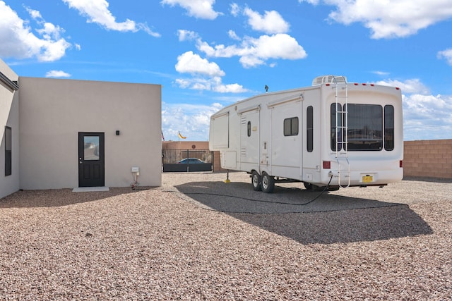 rear view of house with fence and stucco siding