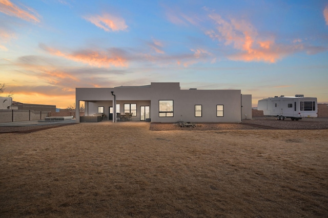 back of property at dusk with a patio and stucco siding