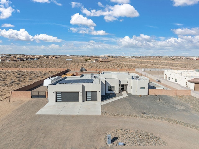 view of front facade featuring driveway, fence, solar panels, and stucco siding