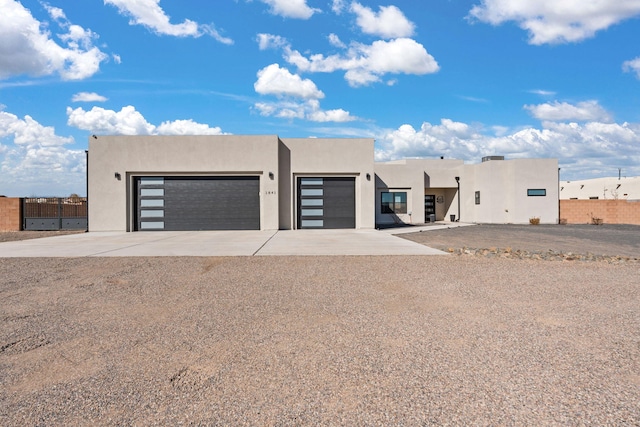 southwest-style home with a garage, concrete driveway, fence, and stucco siding