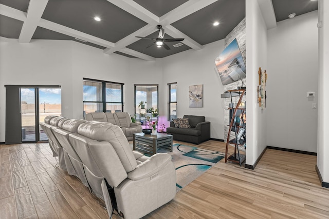 living area with light wood finished floors, coffered ceiling, a high ceiling, and baseboards