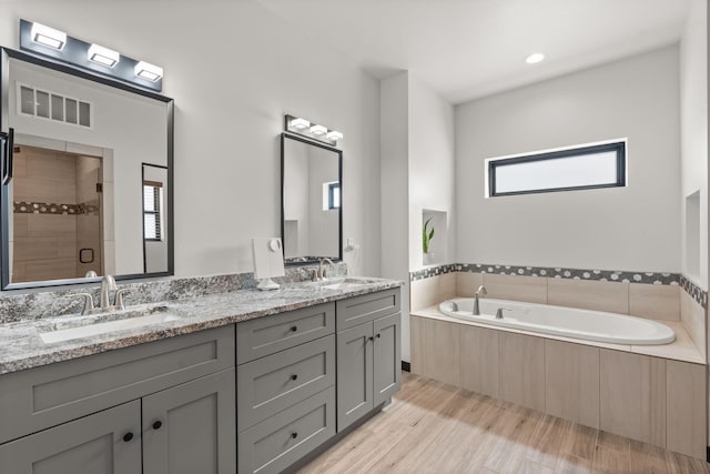 bathroom with wood finished floors, a sink, visible vents, and a shower stall