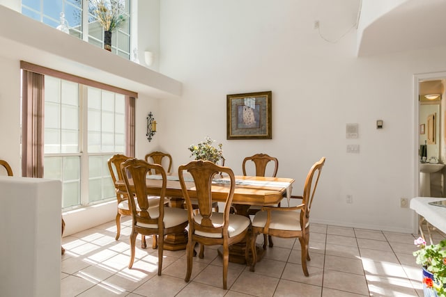 dining room with light tile patterned floors, baseboards, and a towering ceiling