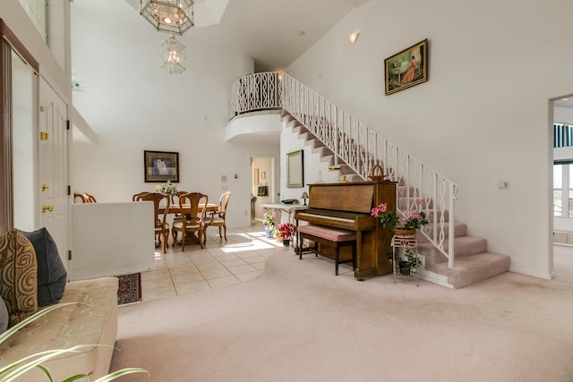 carpeted living room featuring tile patterned floors, stairway, a high ceiling, and a notable chandelier