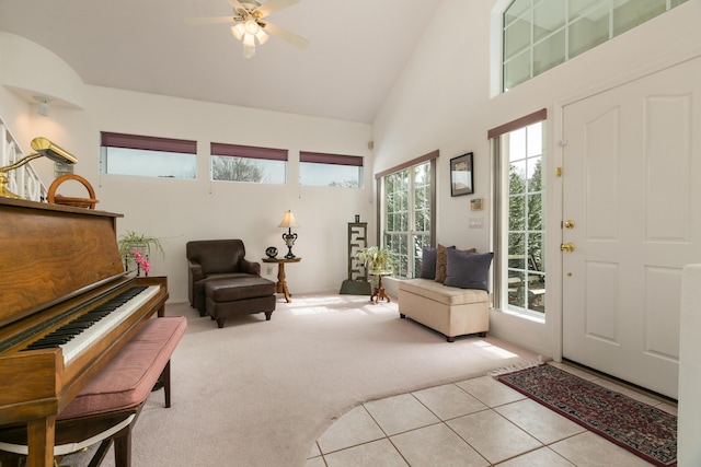 carpeted foyer with tile patterned flooring, high vaulted ceiling, and a ceiling fan