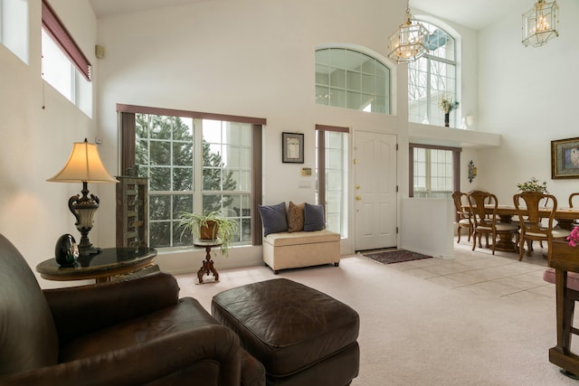 interior space with a high ceiling, a chandelier, tile patterned flooring, and carpet