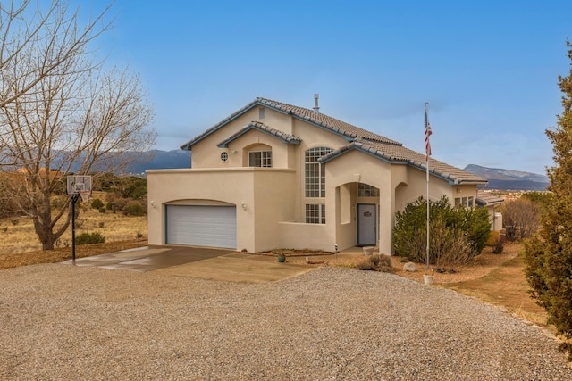 mediterranean / spanish home with concrete driveway, a garage, a mountain view, and stucco siding