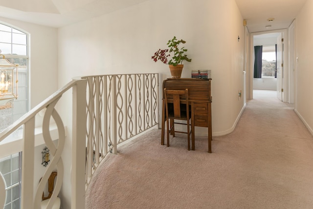 hall featuring carpet flooring, an upstairs landing, and baseboards