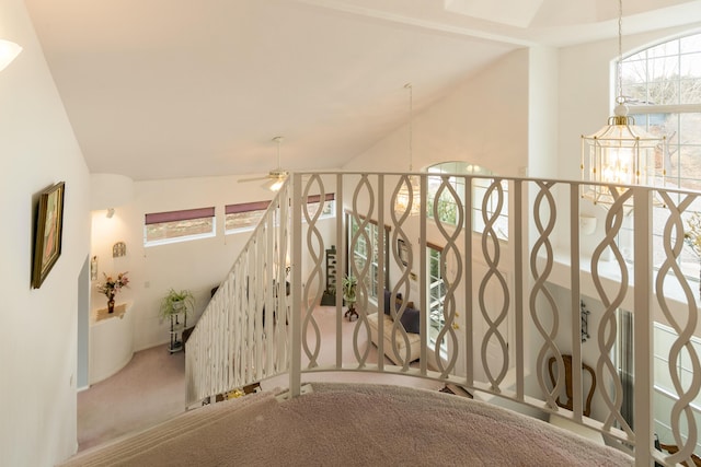 stairway with vaulted ceiling, carpet flooring, and ceiling fan with notable chandelier