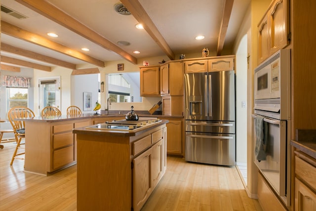 kitchen with stainless steel appliances, light wood-style floors, visible vents, and beamed ceiling