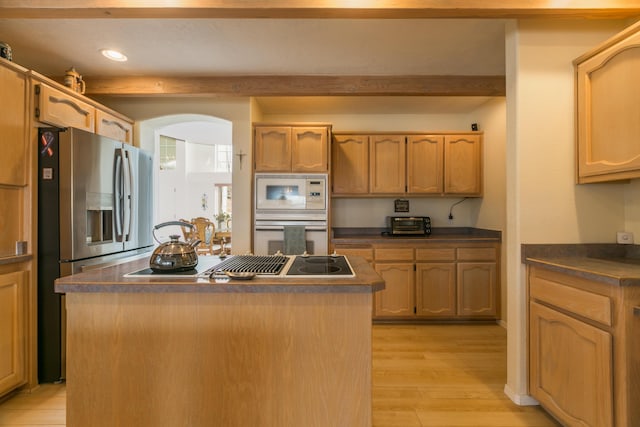 kitchen featuring dark countertops, beamed ceiling, white appliances, and a center island