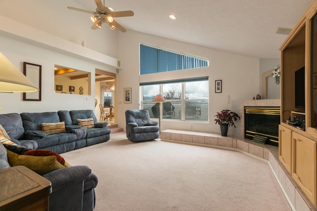 carpeted living area with a tiled fireplace, recessed lighting, high vaulted ceiling, and a ceiling fan