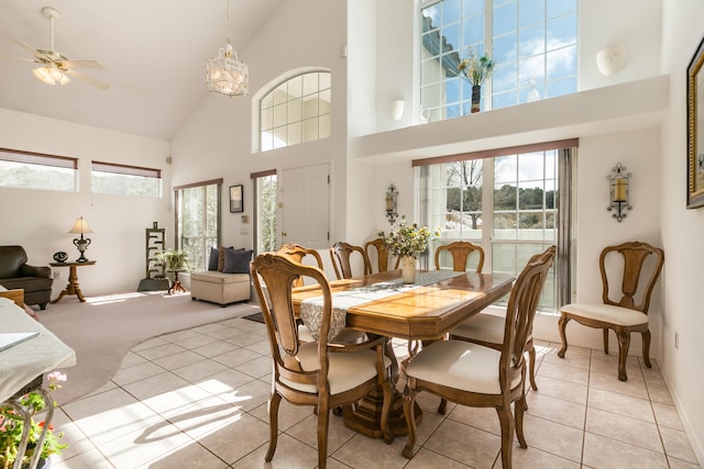 dining room with light tile patterned floors, light colored carpet, high vaulted ceiling, and ceiling fan