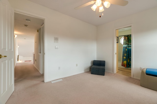 unfurnished room featuring light colored carpet, baseboards, and a ceiling fan