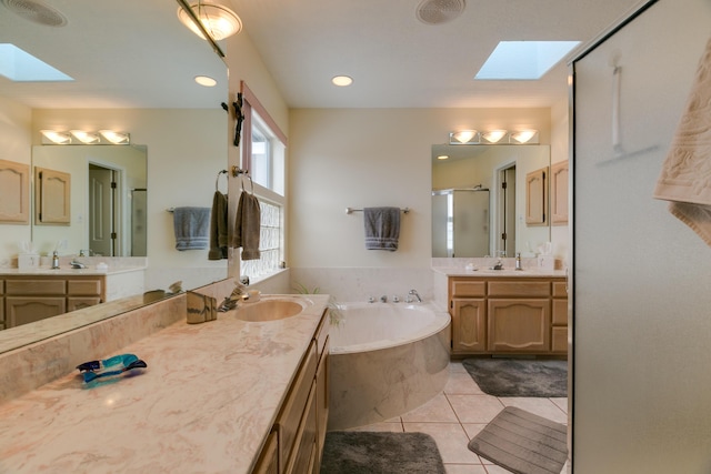 full bathroom with a shower stall, a skylight, a garden tub, and tile patterned floors