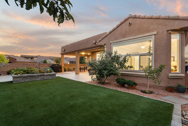 yard at dusk featuring fence and a patio area