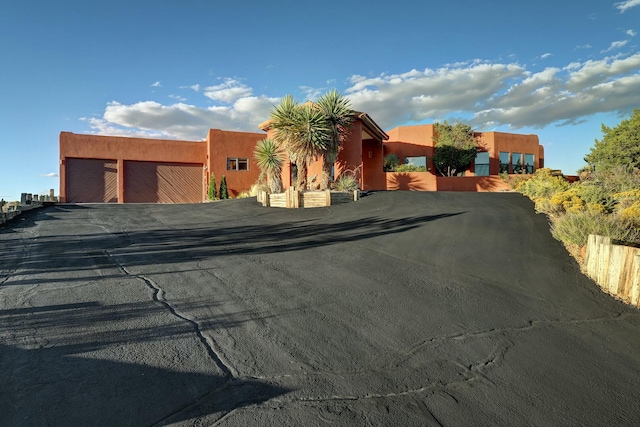 pueblo-style house featuring a garage and stucco siding