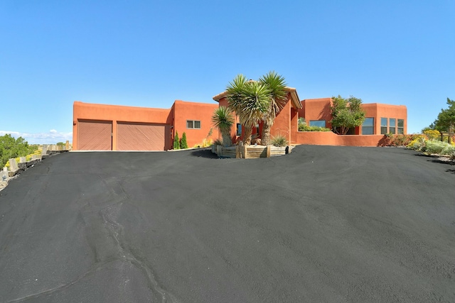 pueblo-style home featuring a garage and stucco siding