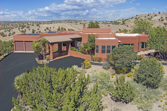 7 Calle Cholla, Placitas, NM 87043 - pueblo-style home with a chimney, an attached garage, stucco siding, and asphalt driveway