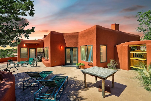 back of house at dusk with a patio and a chimney