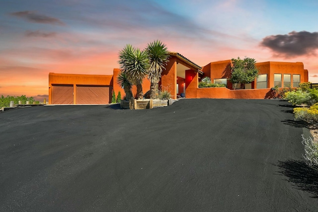 view of front facade featuring aphalt driveway, a garage, and a gate