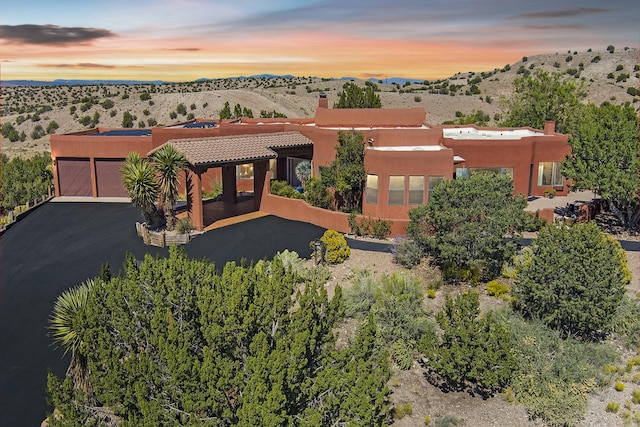 view of front of home featuring stucco siding, driveway, a mountain view, a garage, and a tiled roof