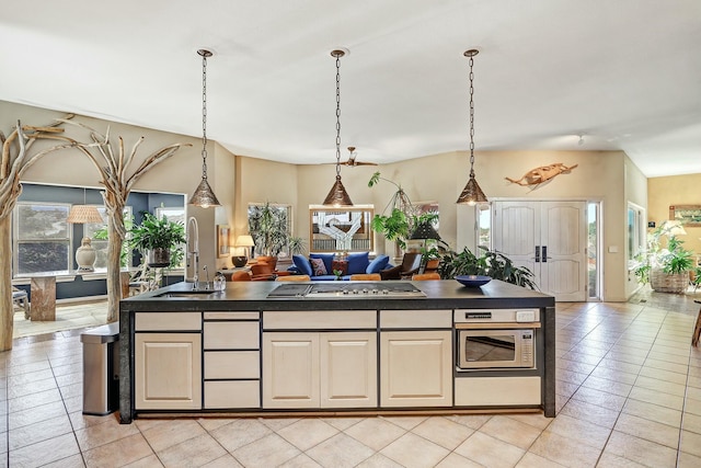 kitchen with a sink, stainless steel appliances, dark countertops, and a kitchen island with sink