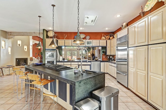 kitchen featuring a breakfast bar, light tile patterned flooring, appliances with stainless steel finishes, dark countertops, and cream cabinets