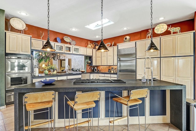 kitchen featuring decorative backsplash, dark countertops, a skylight, and appliances with stainless steel finishes