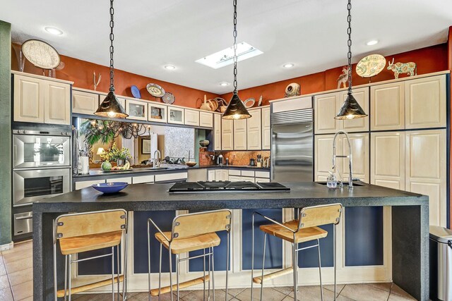 7 Calle Cholla, Placitas, NM 87043 - kitchen featuring appliances with stainless steel finishes, a skylight, dark countertops, a kitchen bar, and recessed lighting