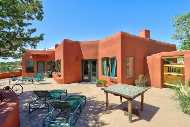 back of property featuring french doors, a chimney, and a patio