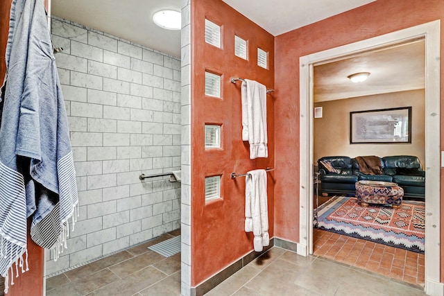 bathroom with tiled shower and tile patterned flooring