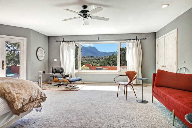 carpeted bedroom featuring access to outside, multiple windows, a ceiling fan, and a mountain view