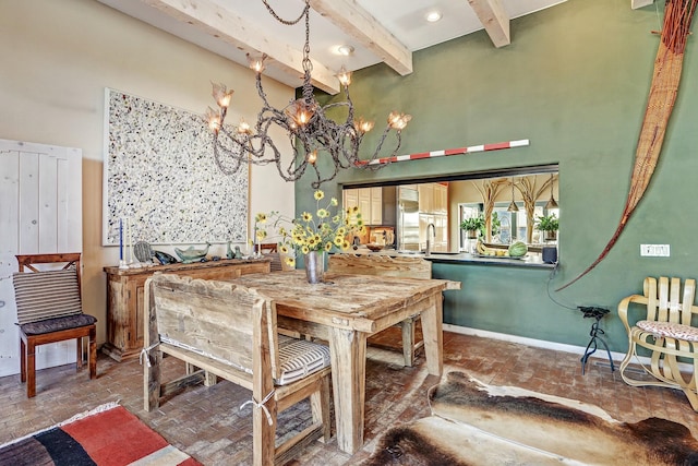 dining area with brick floor, a notable chandelier, baseboards, and a towering ceiling