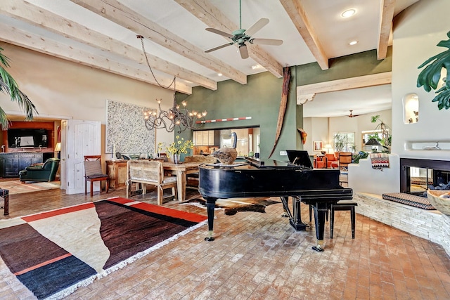 interior space featuring brick floor, beam ceiling, a towering ceiling, and ceiling fan with notable chandelier