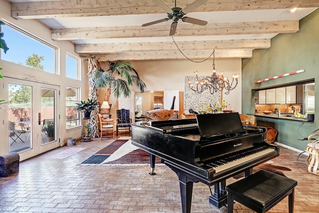 misc room with beamed ceiling, ceiling fan with notable chandelier, french doors, brick floor, and a towering ceiling