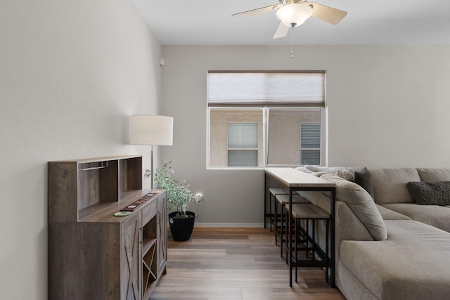 living room featuring ceiling fan, baseboards, and wood finished floors