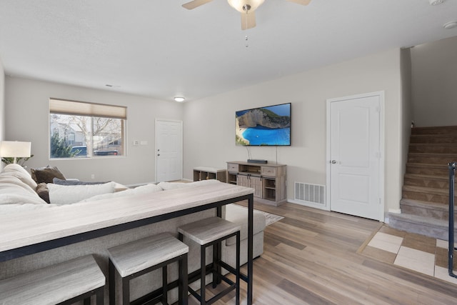 interior space featuring baseboards, visible vents, ceiling fan, wood finished floors, and stairs