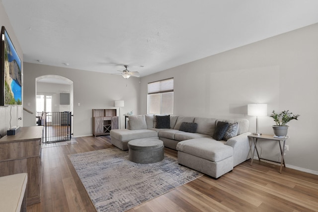 living room featuring baseboards, a premium fireplace, arched walkways, and wood finished floors