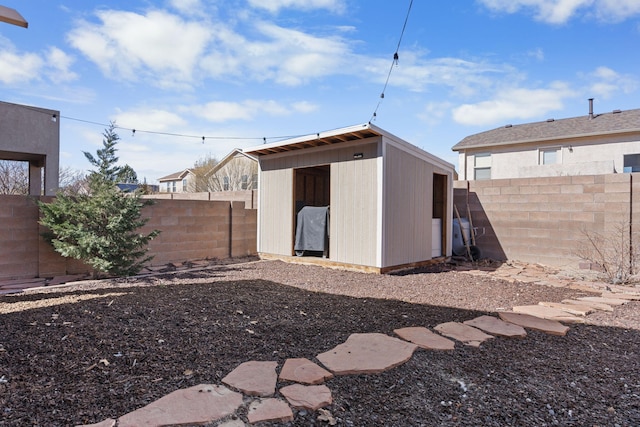 rear view of house with a storage shed, an outdoor structure, and a fenced backyard