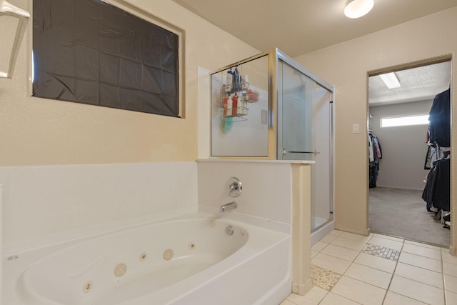 full bathroom with a textured ceiling, a spacious closet, a jetted tub, a shower stall, and tile patterned floors