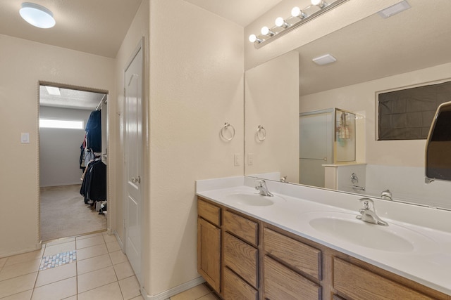 bathroom featuring double vanity, a shower stall, a sink, and tile patterned floors